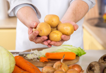 Close-up of a man's hand. The man in the kitchen holds potatoes.