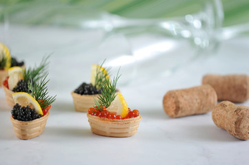 The appetizer is decorated with a slice of lemon and dill. Next a few timid champagne. In the background there are two glasses. Light background. Close-up.