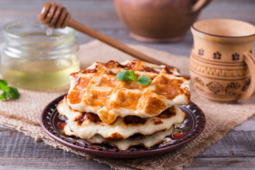 Honey pouring on a fresh waffles. Breakfast with Belgian waffles