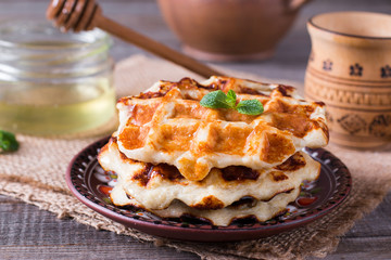 Wafers with honey on a wooden table. Breakfast with Belgian waffles