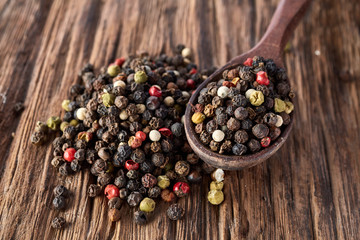 Top view on composition of peppercorn in wooden spoon on vintage wooden background, close-up, shallow depth of field