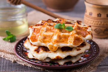 Wafers with honey on a wooden table. Breakfast with Belgian waffles