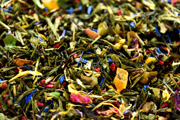 Fototapeta premium Texture of green tea with dried petals of blue flowers, calendula, cornflower. Food background. Organic healthy herbal leaves, detox tea.
