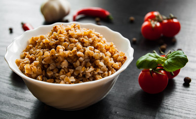Buckwheat porridge kasha in a bowl on dark wooden background