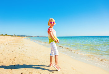 smiling modern child standing in colorful shirt on beach