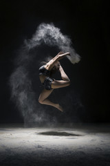 Woman in sportswear jumping in dust cloud view