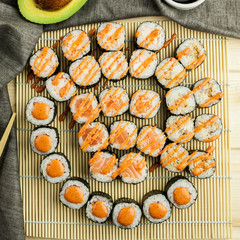 set of different kinds of Japanese sushi rolls with chopsticks and avocado
