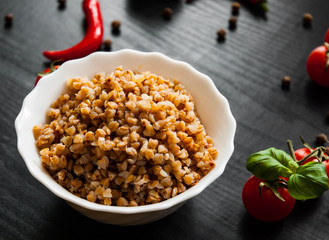 Buckwheat porridge kasha in a bowl on dark wooden background