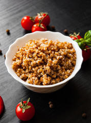 Buckwheat porridge kasha in a bowl on dark wooden background