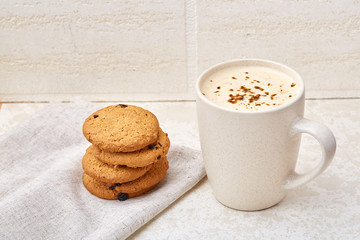Close-up white cup of coffee with chocolate chip cookies on white background, top view