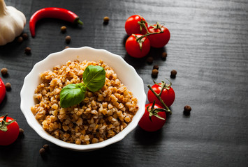Buckwheat porridge kasha in a bowl on dark wooden background