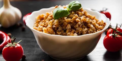 Buckwheat porridge kasha in a bowl on dark wooden background