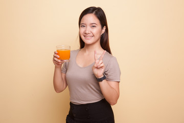 Young Asian woman show victory sign drink orange juice.