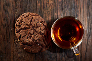Cup of tea with a couple of chocolate cookies on a wooden background, top view