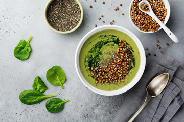 Useful smoothies from spinach with buckwheat flakes in ceramic bowls on gray concrete table background. Selective focus. Top view. Copy space.