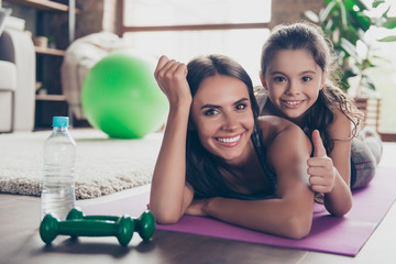 It was cool! Let's do it one more time! Close up photo of excited satisfied cheerful impressed daughter and mother lying on the floor, demonstrating thumb-up symbol, looking in camera