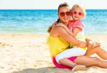 happy modern mother and child sitting on beach