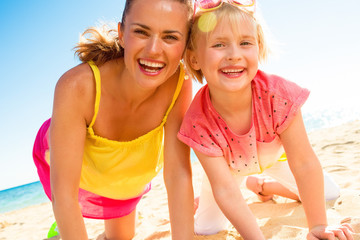 happy trendy mother and child in colorful clothes on beach