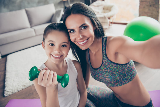 Let's take a picture for social network! Close up portrait of beautiful sportive cute gentle tender mother and daughter wearing sporty clothes making video call via internet connection