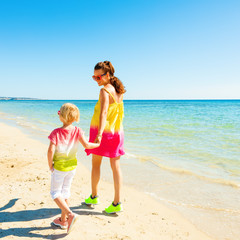 modern mother and daughter on beach walking