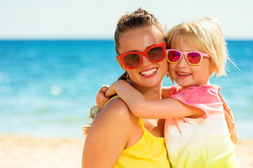happy modern mother and daughter in colorful clothes on beach