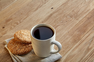 Porcelain teacup with cookies on cotton napkin on a rustic wooden background, top view