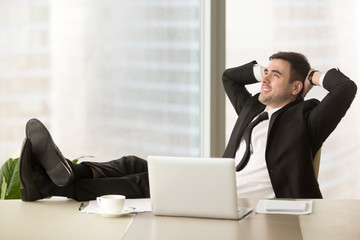 Relaxed businessman feeling positive when resting in office with hands behind head and legs on...