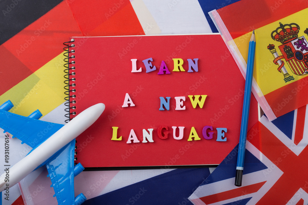 Poster learning languages concept - red notepad and colorful wooden letters with text 