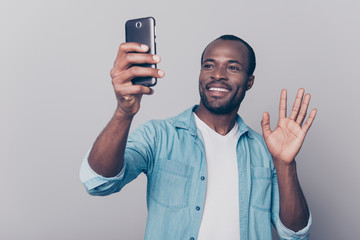 Portrait of cheerful, positive, professional man making selfie on his gadget, electronic, device, holding smart phone in hand, having video-call, sending hello to friend, isolated on grey background