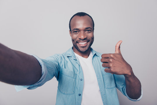 Close up portrait of cheerful excited satisfied glad confident guy wearing jeans casual shirt recommending to visit his place taking selfie demonstrating excellent symbol isolated on gray background