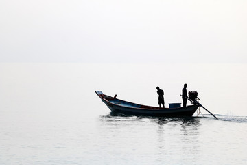 Silhouette of the long tail boat with local people while running in the sea