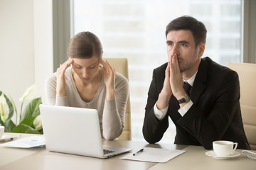 Tired stressed businessman and businesswoman sitting at desk and pondering over problem. Difficult negotiations between business partners, lack of understanding among colleagues, difficulties in work