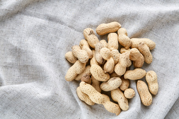 Heap of peanuts on light tablecloth, close-up, shallow depth of field, selective focus, macro