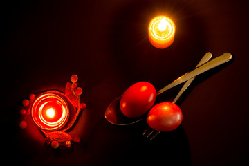 Traditional object for Easter holiday on black background with red eggs and lit candles
