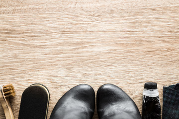 Black, elegant leather boots and cleaning set on the wooden floor. Cares about boots beauty and protection from cold and wet. Preparing for autumn and winter season. Empty place for text or logo.