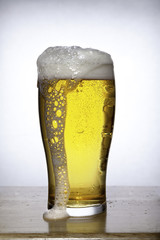 Glass of beer with foam on white