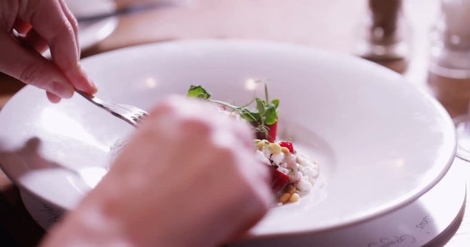 4K Close up on a delicious freshly served gourmet dish with unrecognizable person cutting in & eating