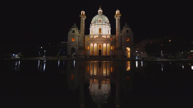 an ultra wide night shot of st charles church reflected in a pool at vienna, austria