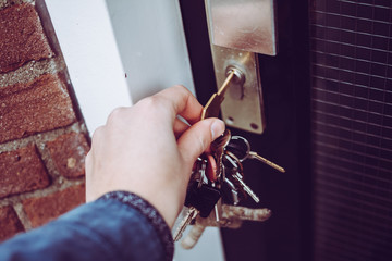 Hand holding bunch of keys opening house door