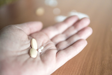 Person holding hand open with different presciption drugs for abuse.