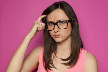 forgetful woman scratching her head on pink background