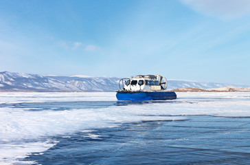 Tourists travel on the ice of a frozen lake Baikal on boats on air cushions " Hivus"