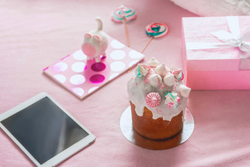 Easter cake, electronic tablet and copybook with present situating on carpet. Decoration concept