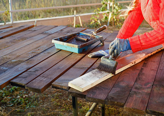 Female hand painting wood with paint roller