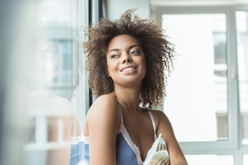 Portrait of pensive african woman watching on street in morning. She situating in room