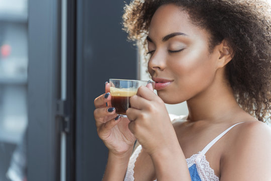 African woman expressing satisfaction while tasting hot beverage in morning