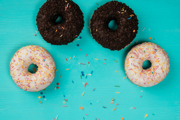 four donuts, chocolate and with white cream, lie on a wooden turquoise background