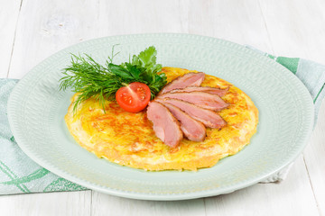 Breakfast of scrambled eggs and meat with tomatoes