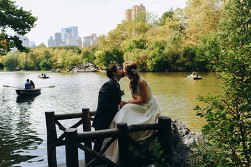 Bride and groom kiss on the bench of a lake in the New York Central Park