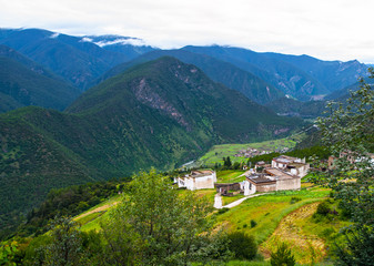 Green hilly landscape of Tibet with small traditional tibetan village.